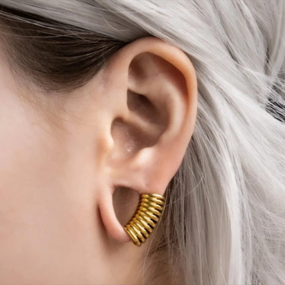 Vrouw draagt een gouden oorlelmanchet, de perfecte samensmelting van kunst en mode