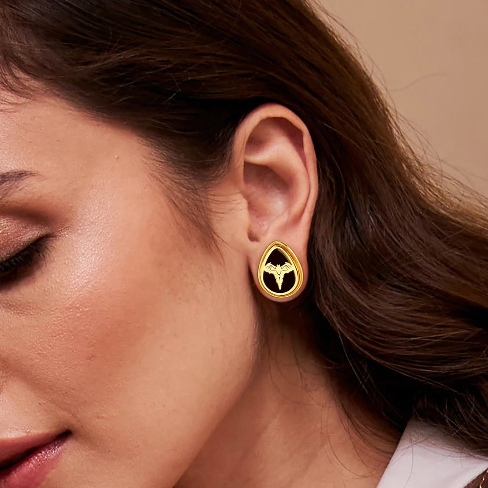 Gouden oorverbreder met vleermuissymbool.